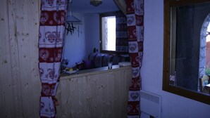 A small kitchen with wooden cabinets, a window, and a curtain with a heart pattern. - Valmorel apartment (4 people 30 m2) back to the skis .Terrace with porch. (Les Avanchers-Valmorel)
