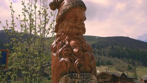 A wooden sculpture of a man with a hat, labeled "Valmore La Belle," set against a mountainous backdrop. - Valmorel apartment (4 people 30 m2) back to the skis .Terrace with porch. (Les Avanchers-Valmorel)