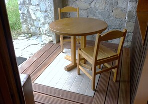 Een houten tafel en stoelen in een kamer met stenen muren en uitzicht op groen.