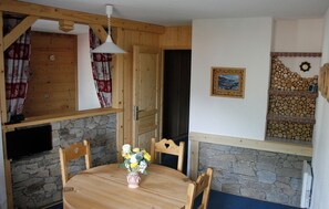 Een houten eettafel met stoelen, een vaas met bloemen en een stenen muur.