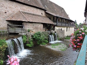 A historic building with a stone facade and a wooden bridge over a small water channel.