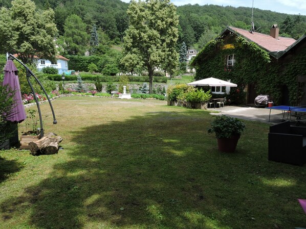 A grassy yard with a swing set, a covered table, and a tennis table.