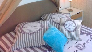 A bedroom with a canopy bed, striped pillows, a nightstand with a lamp, and a wall with a subtle pattern. - Triplex, Beautiful apartment of 50 sqm on 3 levels, up to 4 people (Caen)