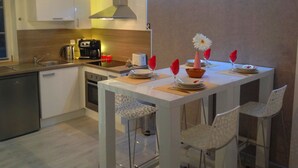 A modern kitchen with a dining area, equipped with a coffee maker, toaster, and a decorative flower centerpiece. - Triplex, Beautiful apartment of 50 sqm on 3 levels, up to 4 people (Caen)