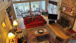 A spacious living room with a red sofa, leather armchairs, a coffee table, and a fireplace.