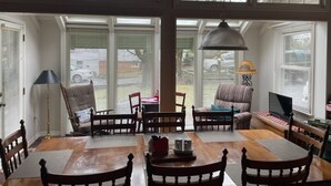A spacious room with a large wooden dining table, several chairs, a sofa, and a television.