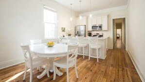 A modern kitchen with white cabinetry, a central island, and a dining area with white chairs and a round table.