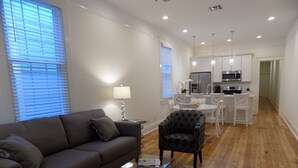 A modern living room with a grey sofa, a patterned armchair, and a glass coffee table.