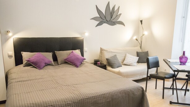 A bedroom with a bed, two pillows, a nightstand, a lamp, a chair, and a table.