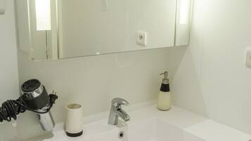A bathroom with a white sink, a mirror, a towel rack, and a bottle of hand soap.