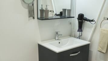 Une salle de bain avec des toilettes blanches, un lavabo avec un miroir au-dessus et un porte-serviettes.