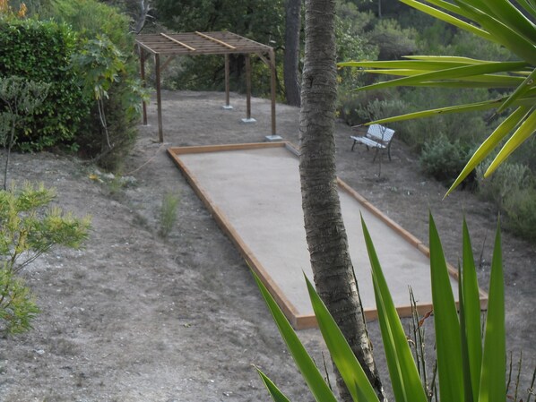 A garden with a pergola, a bench, and a sandbox.