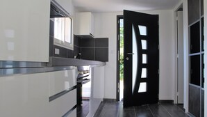Una cocina moderna con extractor de acero inoxidable, armarios blancos y piso de baldosas oscuras.