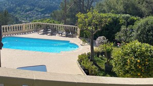Zona de piscina con sillones reclinables y vistas a un paisaje montañoso.