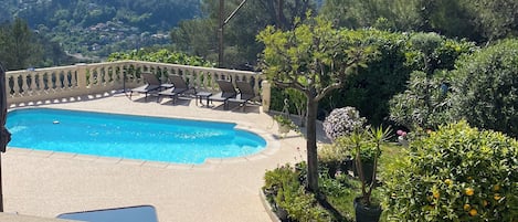 A pool area with lounge chairs and a view of a mountainous landscape.