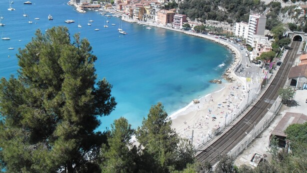 Un pueblo costero con playa, barcos y una vía de tren.