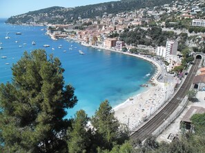 A coastal town with a beach, boats, and a railway track.