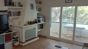 Ein Wohnzimmer mit Flachbildfernseher, Bücherregalen, Heizkörper und einer Schiebetür zu einer Außenpatio.