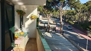 Ein Balkon mit kariertem Tischleinen, einer gelben Schüssel und hängenden Pflanzen.