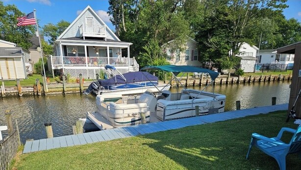 Un muelle con barcos, un área verde y una casa con porche.