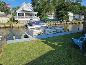 Un muelle con barcos, un área verde y una casa con porche.