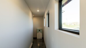 Un couloir étroit avec une fenêtre sur la droite, une porte au fond et une décoration murale à motifs en chevron.