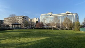 Ein Park mit einem Pavillon und einem modernen Gebäude mit Glasfenstern.