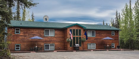 A wooden lodge with a green roof, two flagpoles, and a windmill.