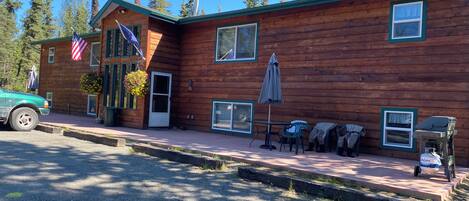 A wooden cabin with a porch, a table with chairs, and a flag.