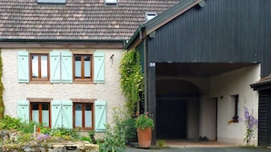 Un bâtiment avec un toit recouvert de tuiles, une entrée abritée et une enseigne portant le numéro « 38 ».