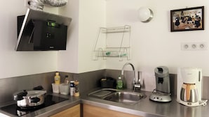 Une cuisine moderne équipée d’une cuisinière intégrée, d’un évier, d’une machine à café et d’un porte-ustensiles fixé au mur.