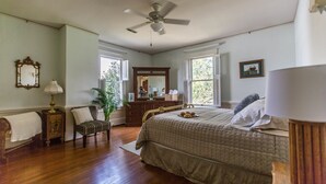 Un dormitorio con una cama grande, un aparador, un espejo y un ventilador de techo.