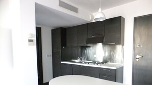 Una cucina moderna con mobili scuri, un piano di lavoro bianco e una cappa aspirante in acciaio inossidabile.