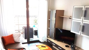Un soggiorno moderno con un divano, un tavolino, una TV e un'area pranzo.