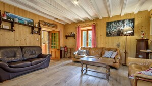 Un salon chaleureux au parquet en bois, avec un canapé en cuir marron, une table basse en bois et un fauteuil en cuir couleur fauve.