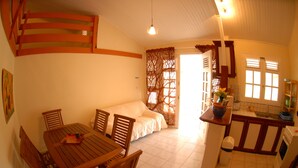 Ein gemütliches Zimmer mit Esstisch, Stühlen, einem Bett und einer Küchenzeile.