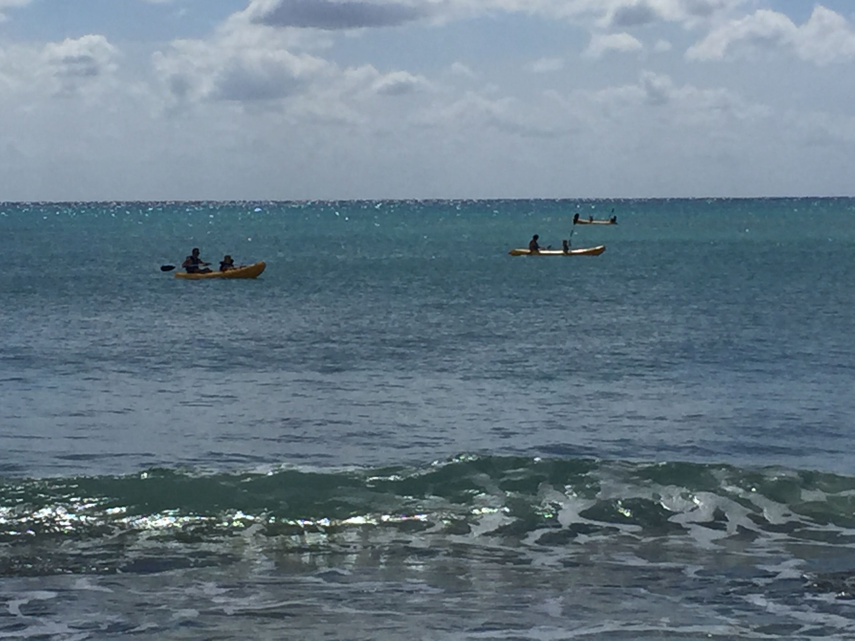 Mar tranquila con kayaks y una pequeña embarcación.