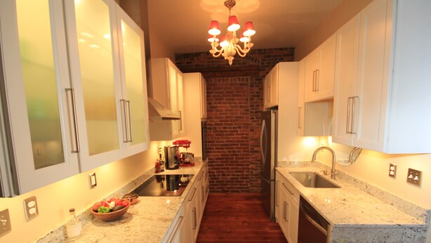 A modern kitchen with granite countertops, stainless steel appliances, and a brick wall. - In the Heart of Historic Downtown Paris KY (Paris)