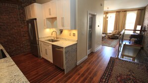 A modern kitchen with granite countertops, stainless steel appliances, and a brick accent wall. - In the Heart of Historic Downtown Paris KY (Paris)