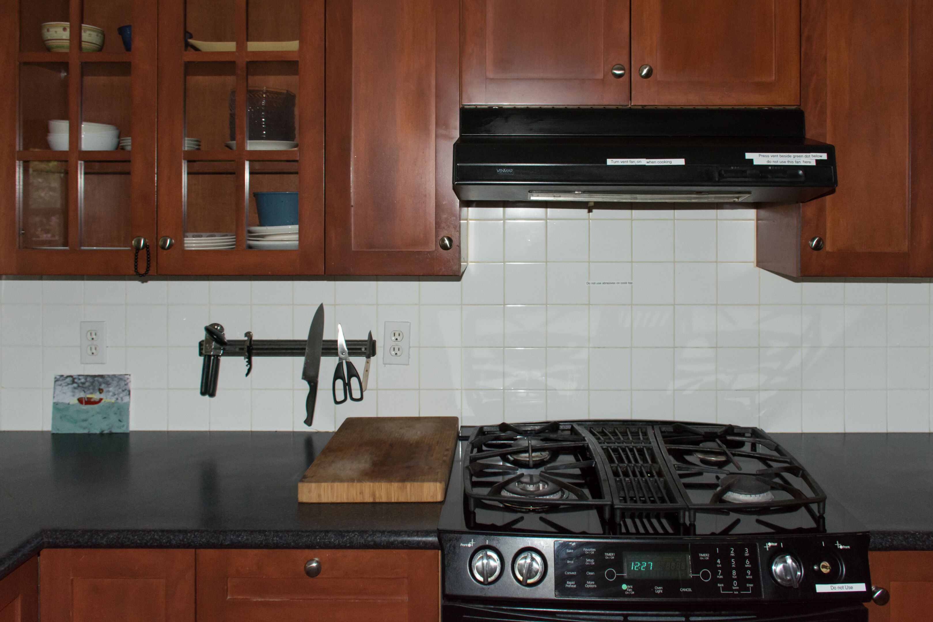 A kitchen with wooden cabinets, a gas stove, and a wall-mounted knife holder.