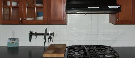 A kitchen with wooden cabinets, a gas stove, and a wall-mounted knife holder.