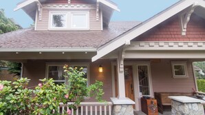 A two-story house with a gabled roof, a front porch, and a stone fireplace. - Everyone Welcome, Cozy retreat walking distance to  Butchart Gardens. (Brentwood Bay)
