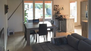 Een moderne woonkamer met een bank, een eettafel met stoelen en een keuken met een bar.