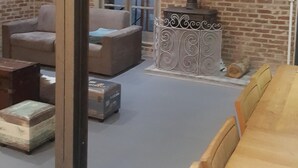 A living room with a brick wall, a fireplace, a sofa, a table, and a window.