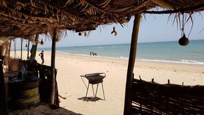 A beachside hut with a thatched roof, a grill, and a view of the ocean. - DOLMEN DE M'BOUR - Your next dream vacation, 5 min from the ocean (M'bour)