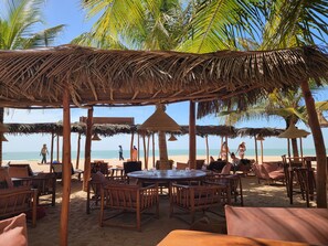 A beachside restaurant with thatched umbrellas, wooden furniture, and a view of the ocean. - DOLMEN DE M'BOUR - Your next dream vacation, 5 min from the ocean (M'bour)