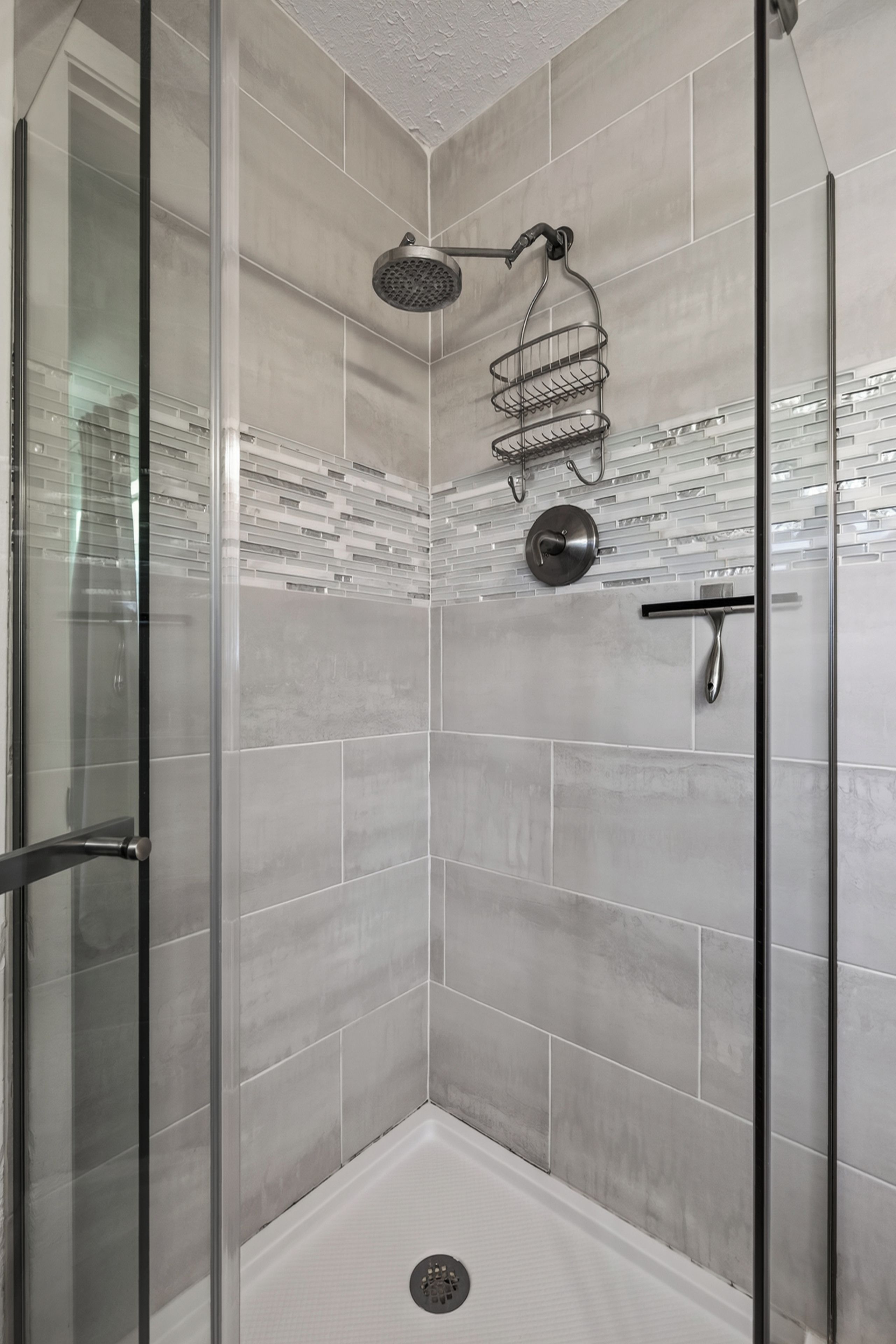 A modern shower with a glass door, a rain showerhead, and a metal towel rack.