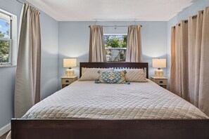 A bedroom with a bed, two bedside tables, a window with curtains, and a view of the outdoors. - St Augustine Anastasia House close to Downtown & Beaches, King beds in each room (St Augustine)