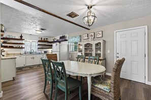A dining area with a round table, chairs, and a ceiling fan.