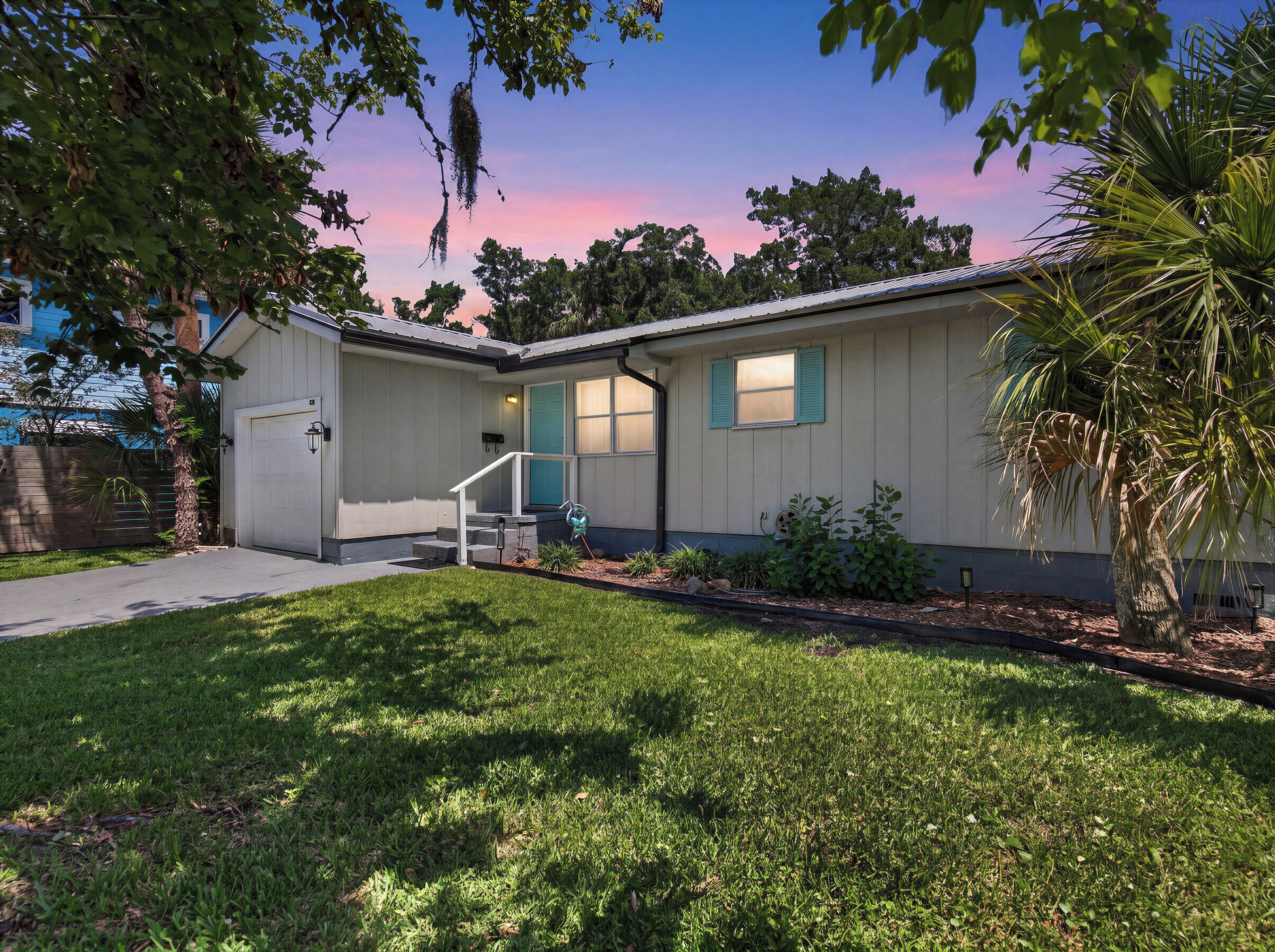 A residential house with a front porch, a garage, and a well-maintained lawn.